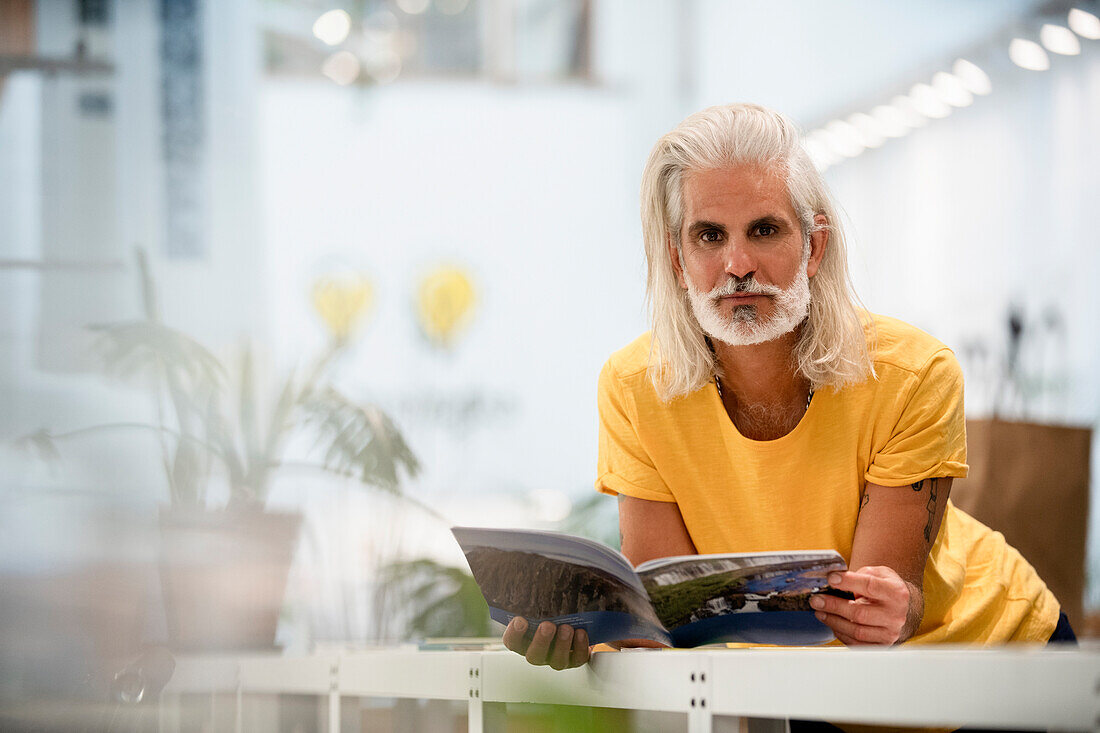 Adult male designer leaning on table while looking at the camera