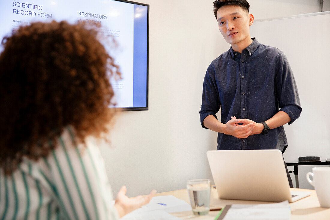 Project manager listening to female coworker during presentation