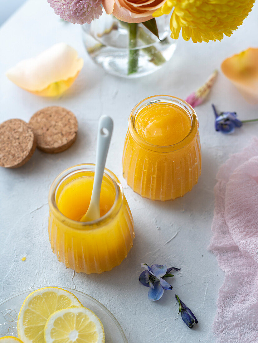 Zitronenquark in Gläsern, dekoriert mit Frühlingsblumen und Pastellfarben