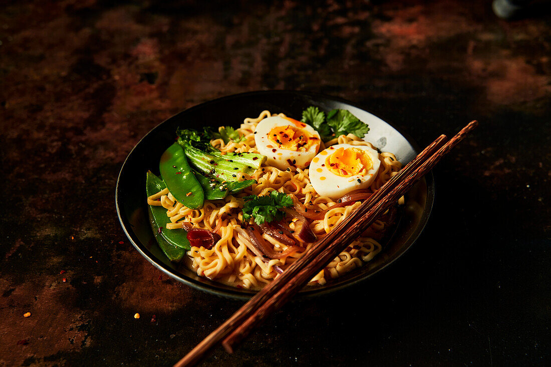 Egg and vegetable noodles in a bowl with chopsticks