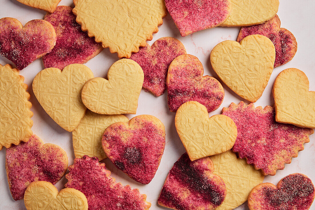 Die-cut heart biscuits with pink sugar on a pink marble background