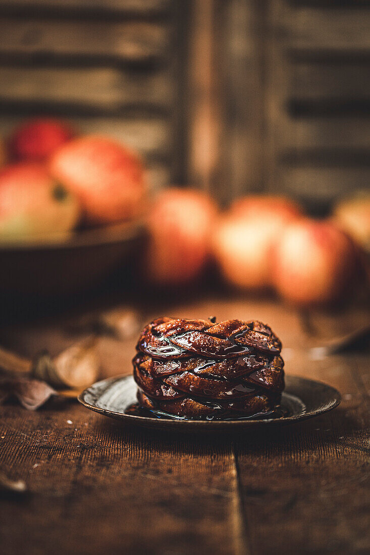 A decorative baked apple, served on a plate, covered with sauce