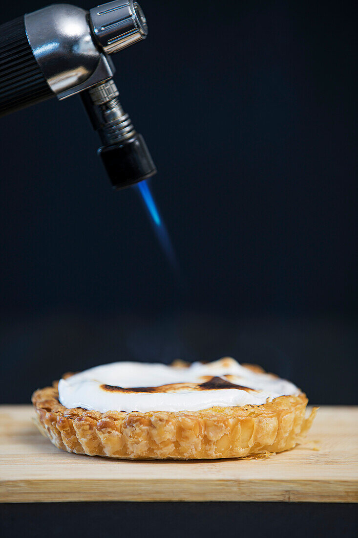 A blowtorch browns the top of a meringue pie
