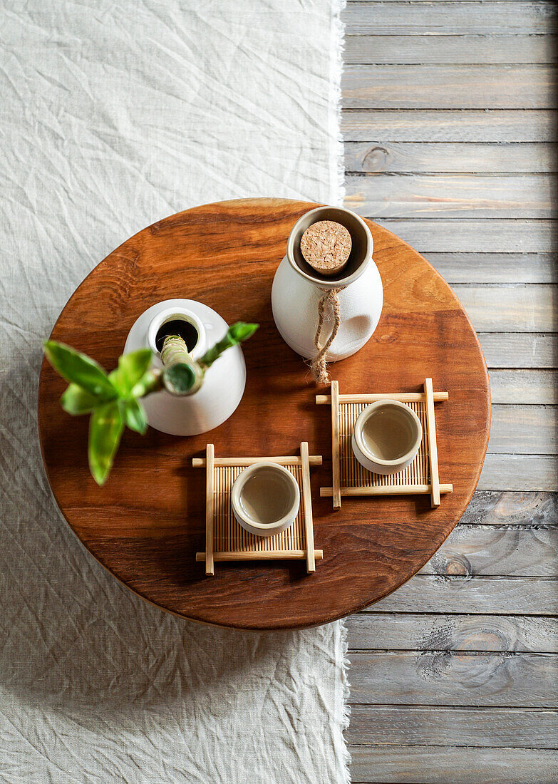 Japanese sake still life with a bamboo branch, light-coloured linen background, Asian ceremony