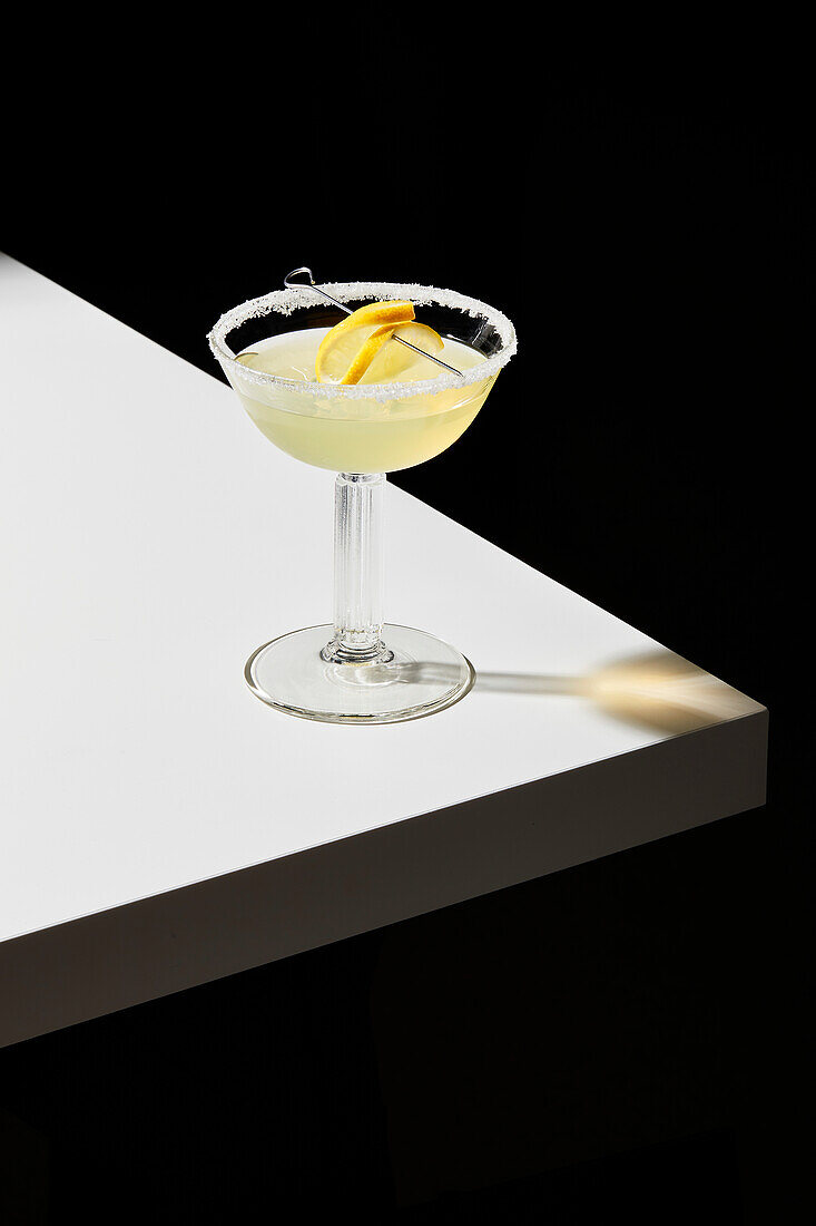 Lemon cocktail on a white table and black background