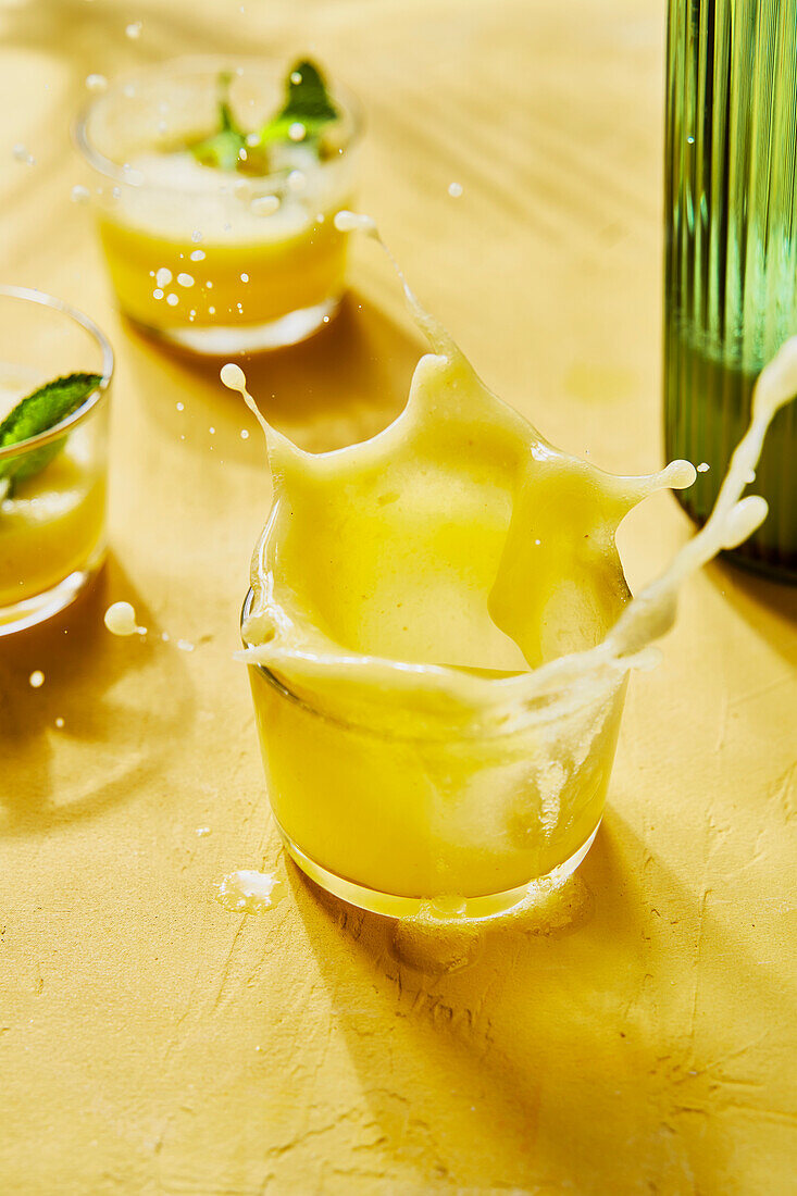Ananas-Minze-G&T-Spritzer vor gelbem Hintergrund mit Schatten