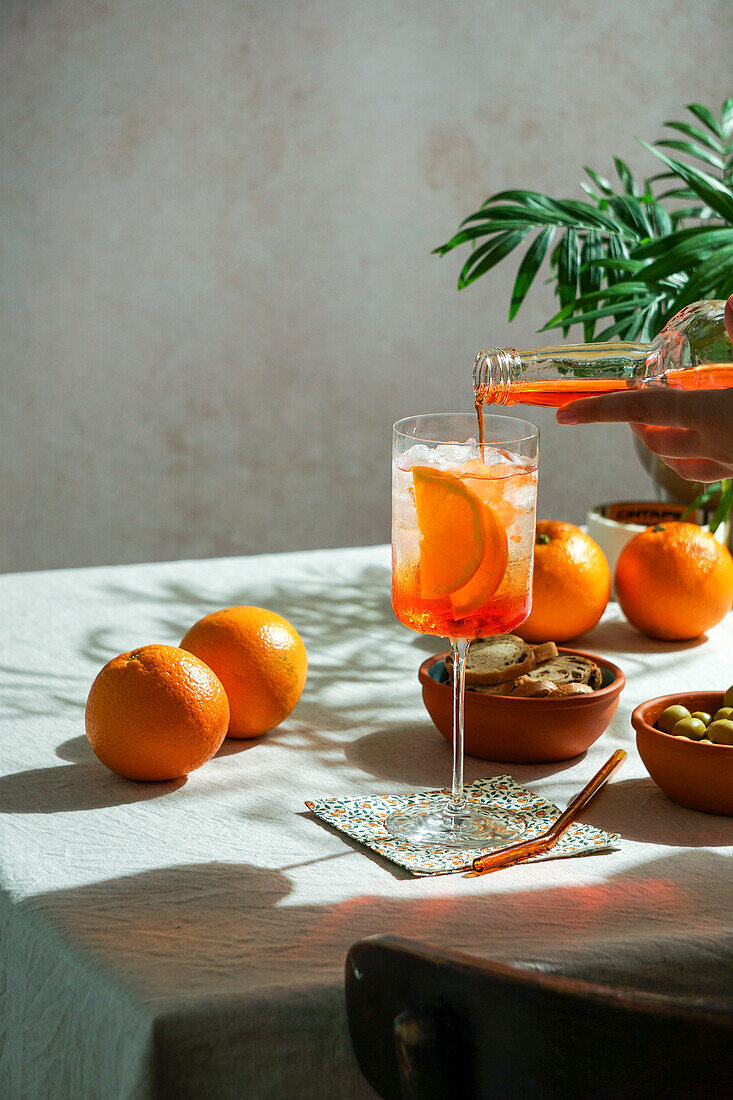 Aperol Spritz, cocktail, on a linen tablecloth, shadow, harsh sunlight, summer drink in a glass