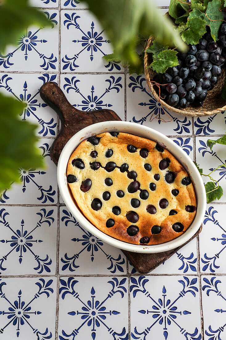 Rote Weintrauben-Clafoutis, französische Küche. auf einem Tisch aus Keramikfliesen mit blauem Muster