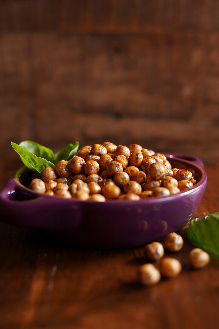 Basil and paprika roasted chickpeas on wooden background. Negative copy space.