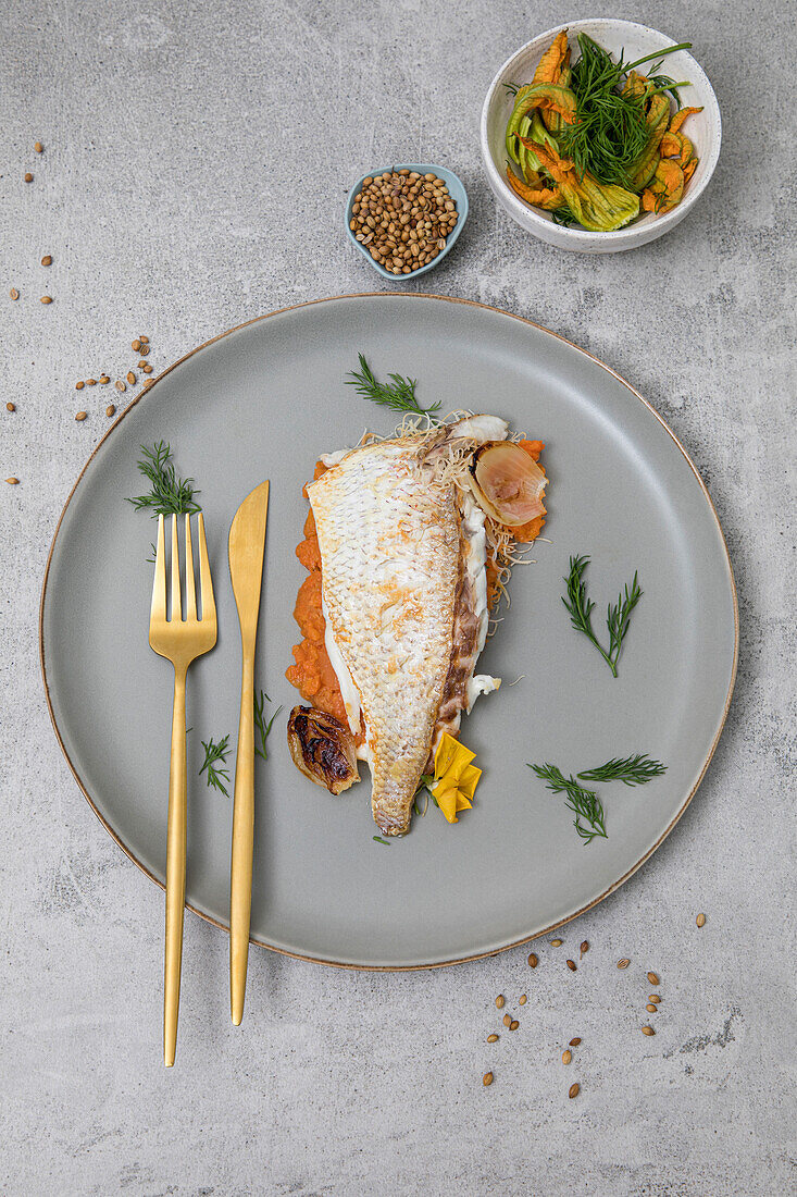 Freshly baked market fish, served with fresh vegetables on a grey plate