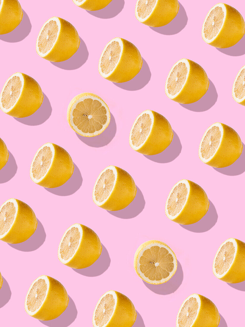 Full frame with juicy lemon halves against a light pink background