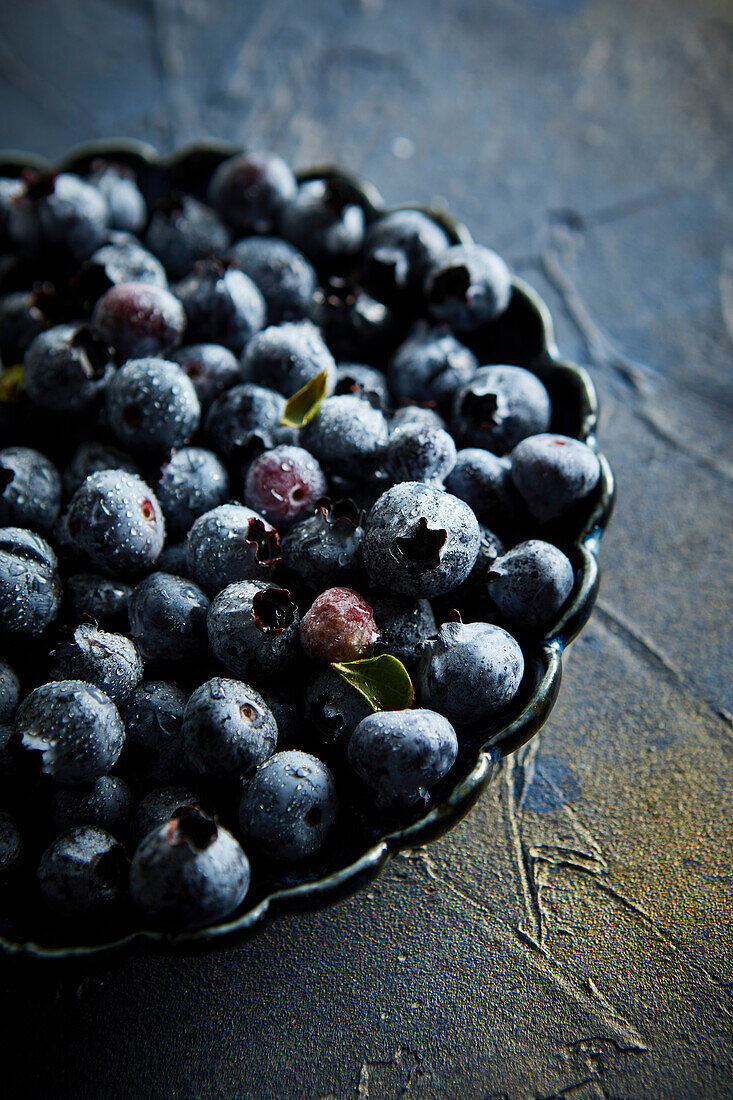 Blueberries with water droplets against a blue background