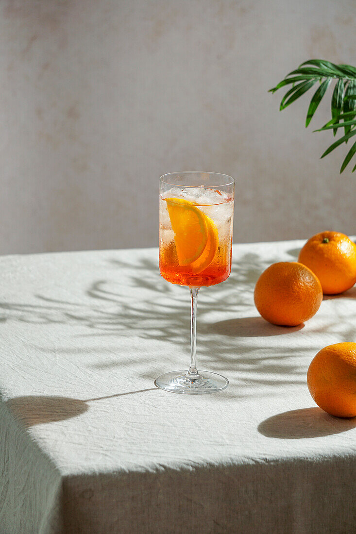 Aperol Spritz, Cocktail, auf einer Leinentischdecke, Schatten, hartes Sonnenlicht, Sommergetränk im Glas