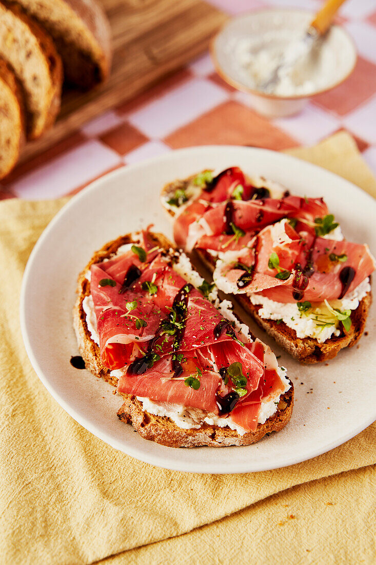 Ricotta and Parma Ham Toast with Balsamic Drizzle and Cress on a tiled background