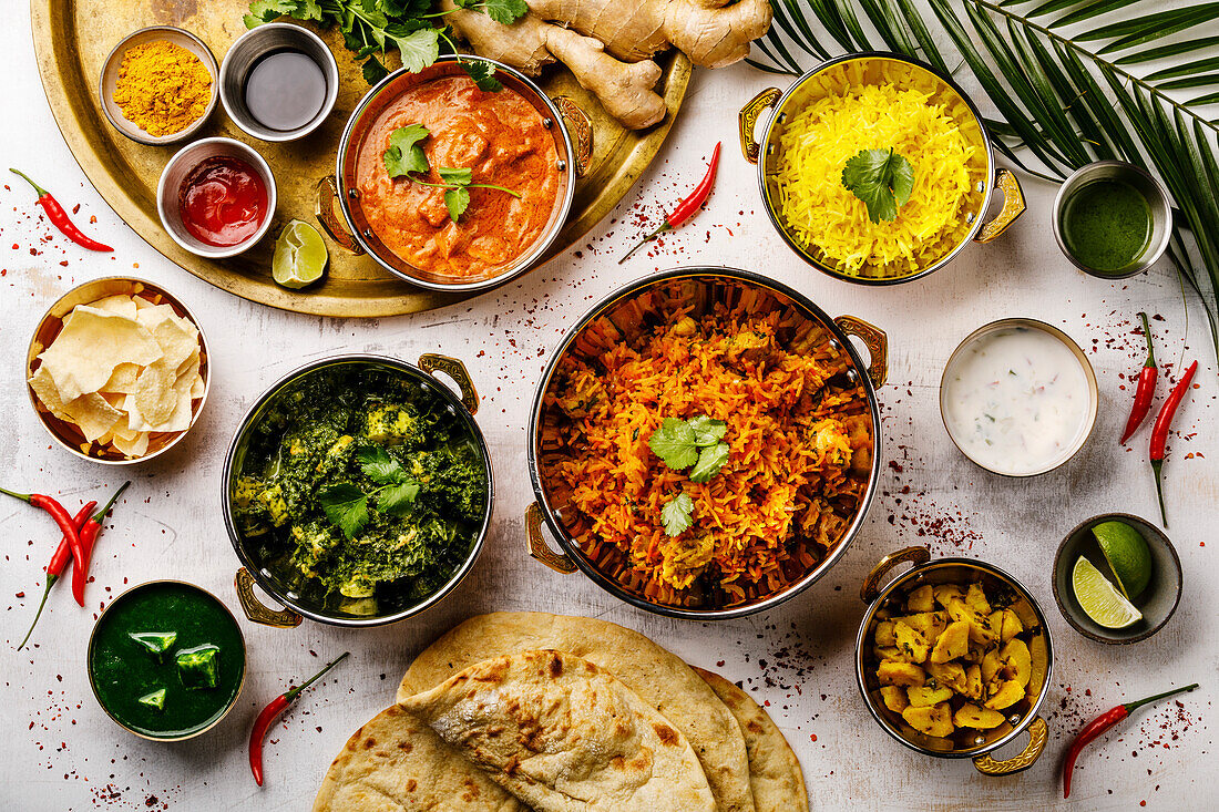 Indian food Curry butter chicken, palak paneer, chiken tikka, biryani, papad, dal, rice with saffron and naan bread on a white background