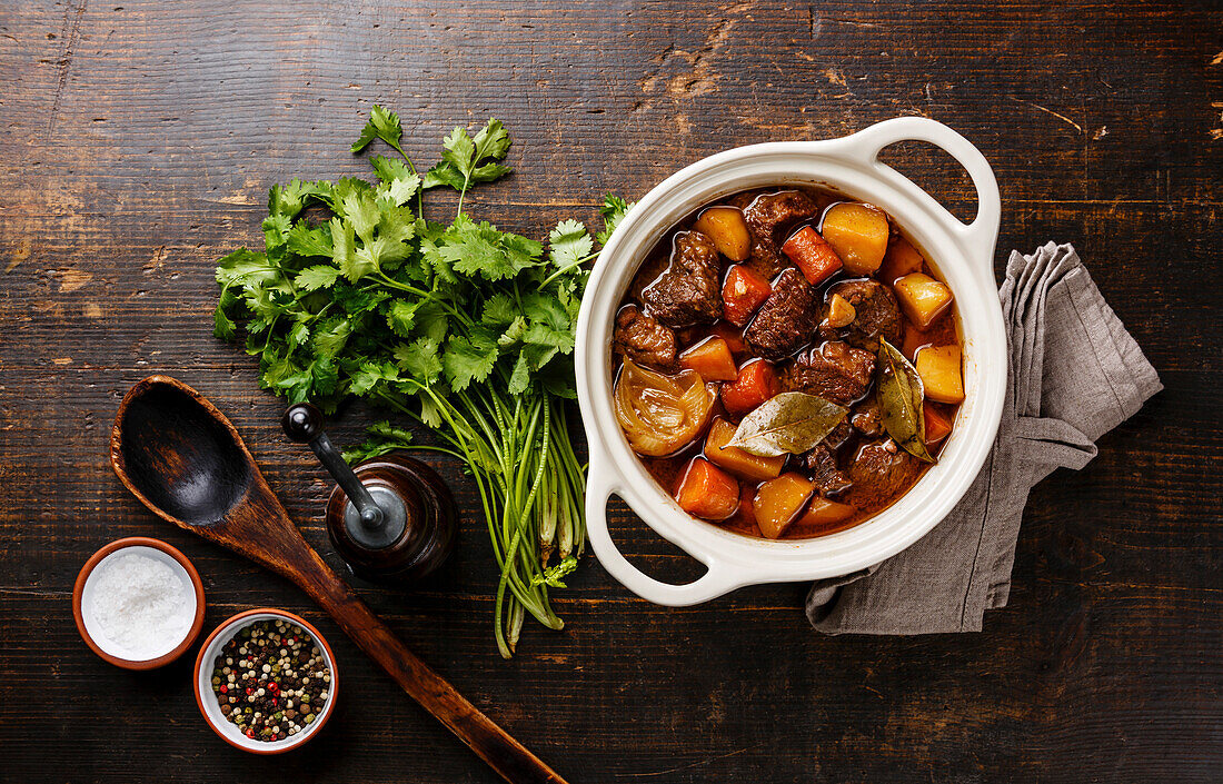 Braised beef with potatoes, carrots and spices in a ceramic pot