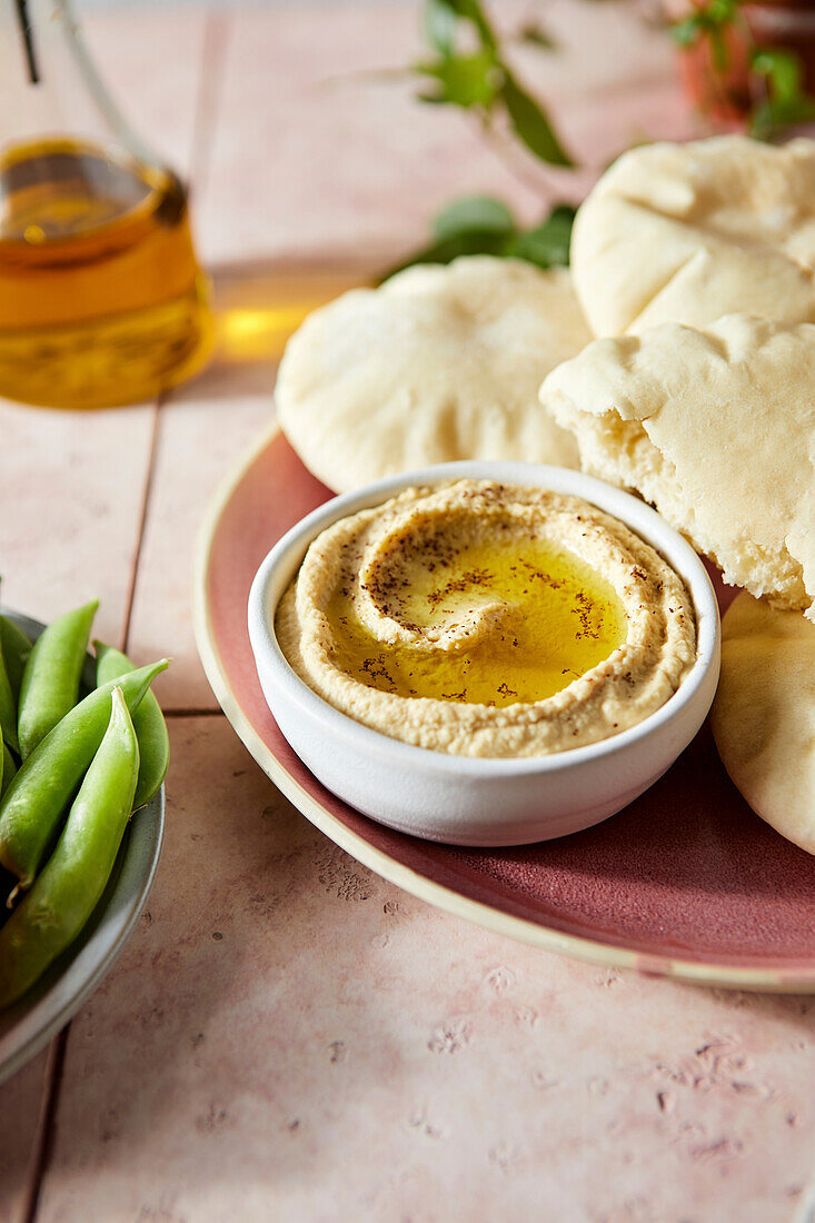 Fladenbrot und Hummus auf rosa Fliese