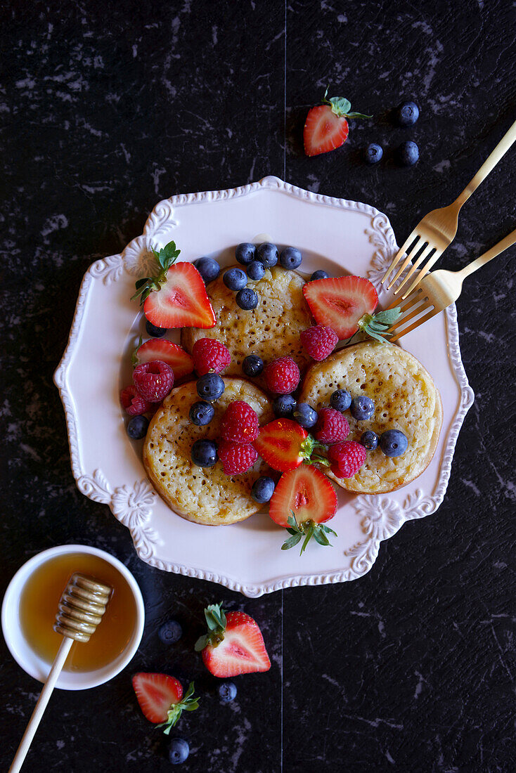 Englisches Gebäck mit Beeren und Honig auf schwarzem Marmor, Flatlay Nahaufnahme