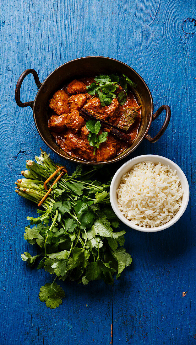 Chicken Tikka Masala würziges Curry Fleischgericht mit Reis auf blauem Holzhintergrund