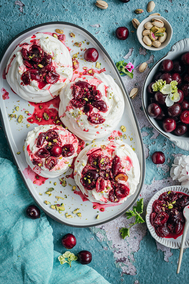 Meringues mit frischer Sahne und reifen Kirschen auf blauem Hintergrund