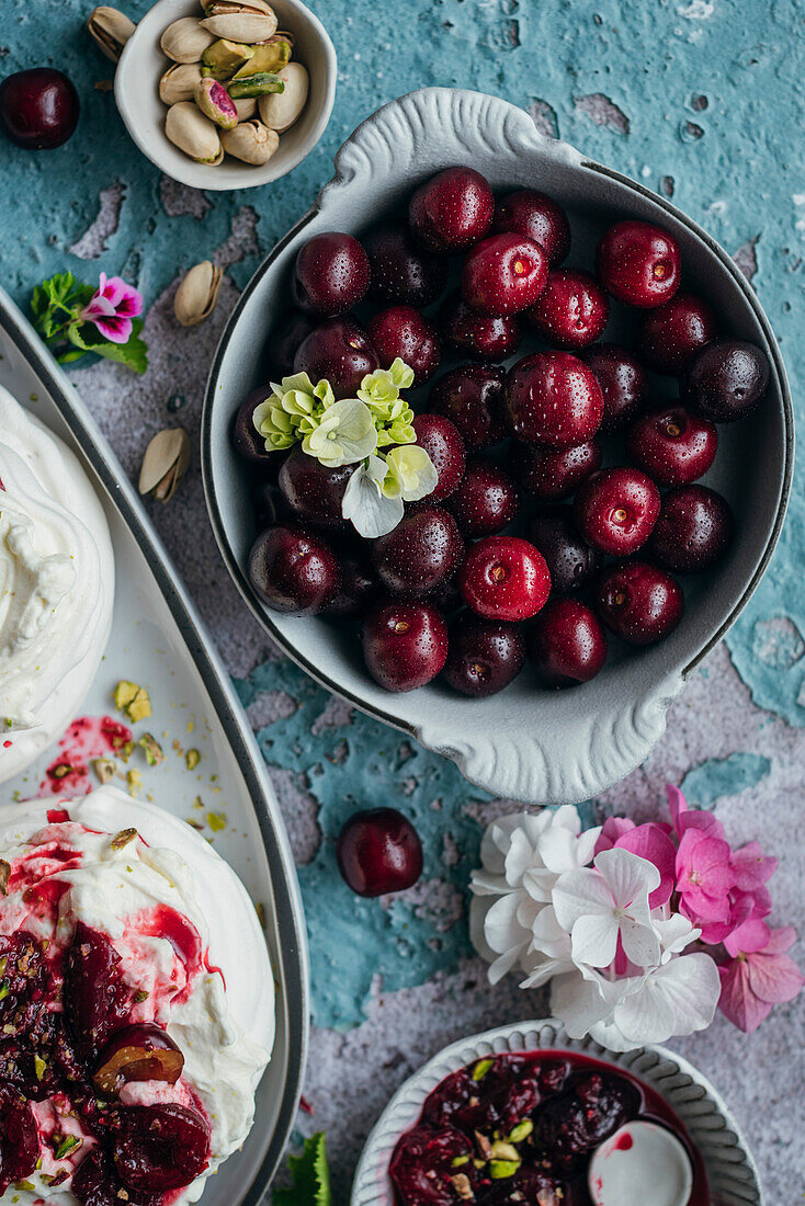 Meringues mit frischer Sahne und reifen Kirschen auf blauem Hintergrund