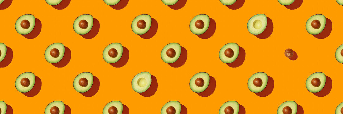 Banner. Avocado on orange background pattern top view lay flat. Summer colour. Minimal concept