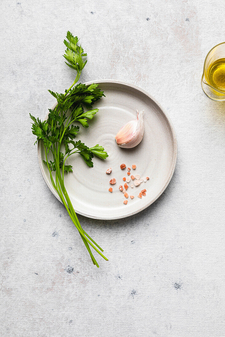 Petersilie, Knoblauch und rosa Salz auf einem Teller, bereit für die Zubereitung eines Gewürzes