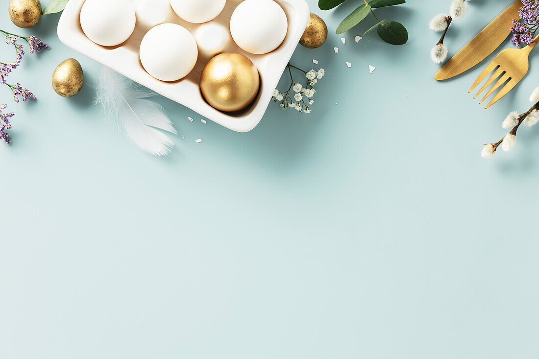Ostern Tischdekoration. Fröhliche Ostern Konzept mit goldenem Tischgedeck, Ostereiern, Federn und Frühlingsblumen. Ostern Hintergrund mit Kopie Raum. Flachlage