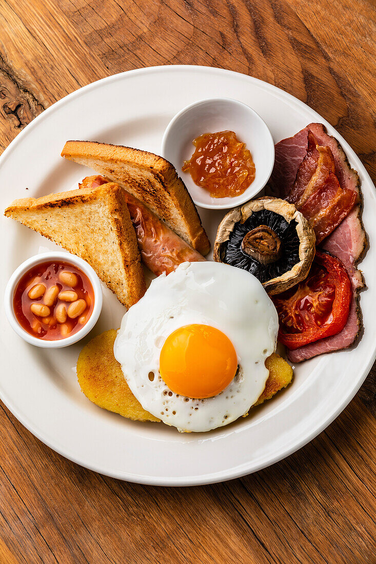 Komplettes englisches Frühstück mit Spiegeleiern, Würstchen, Speck, Bohnen und Toast