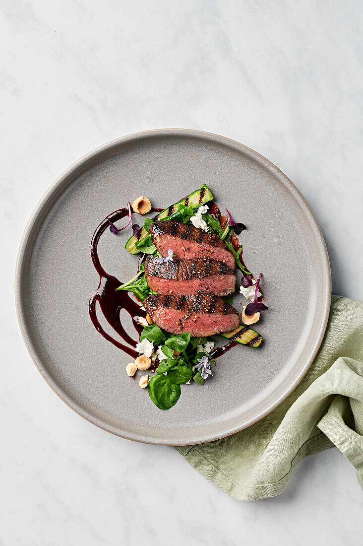 Ras el hanout lamb fillet, balsamic glaze, Persian fetta, grilled courgette, rocket, watercress and roasted hazelnuts