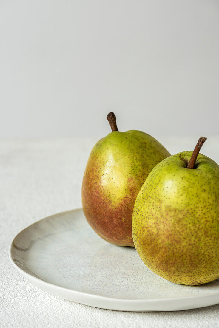 Pears on a plate against a light-coloured background. Place to copy