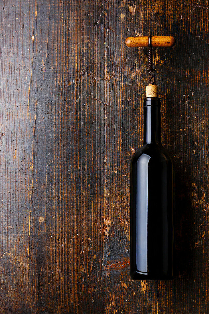Weinflasche und Korkenzieher auf dunklem Holzhintergrund