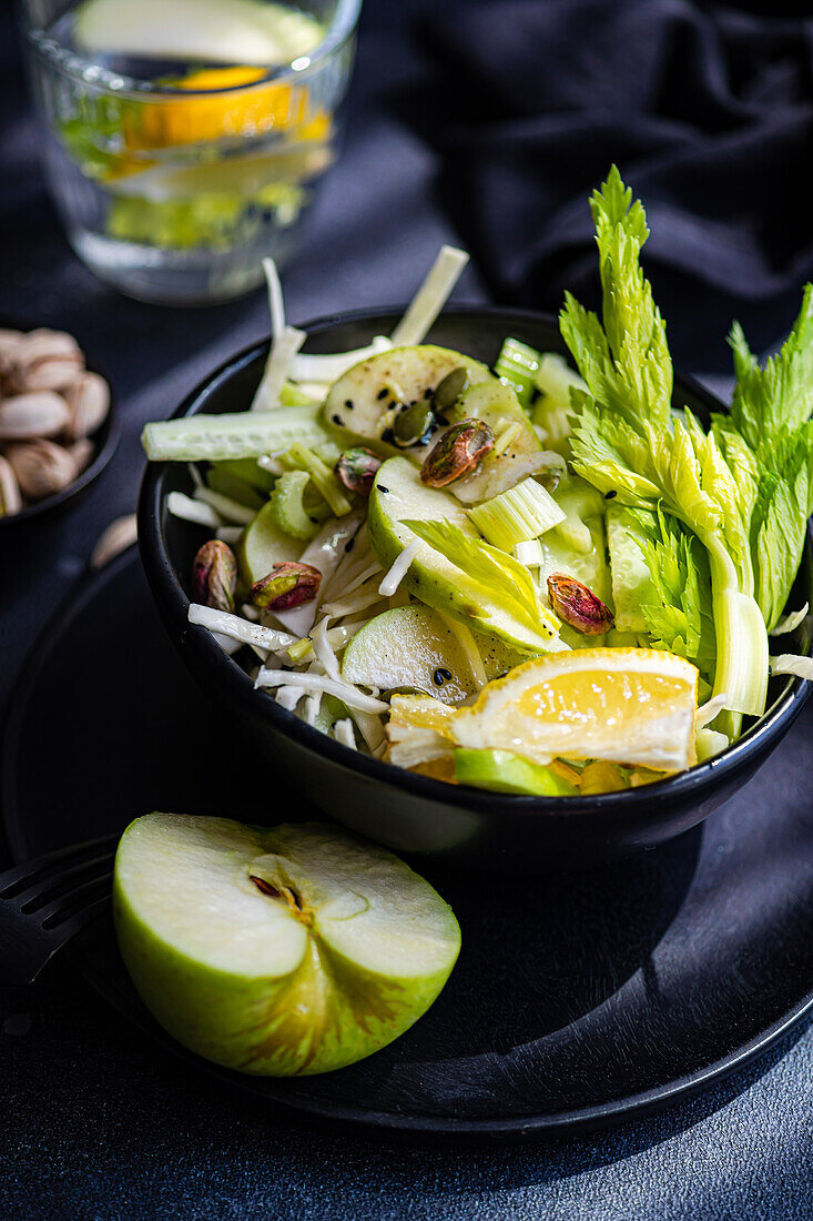 Healthy celery salad with apples and seeds, served in a bowl with a dark background