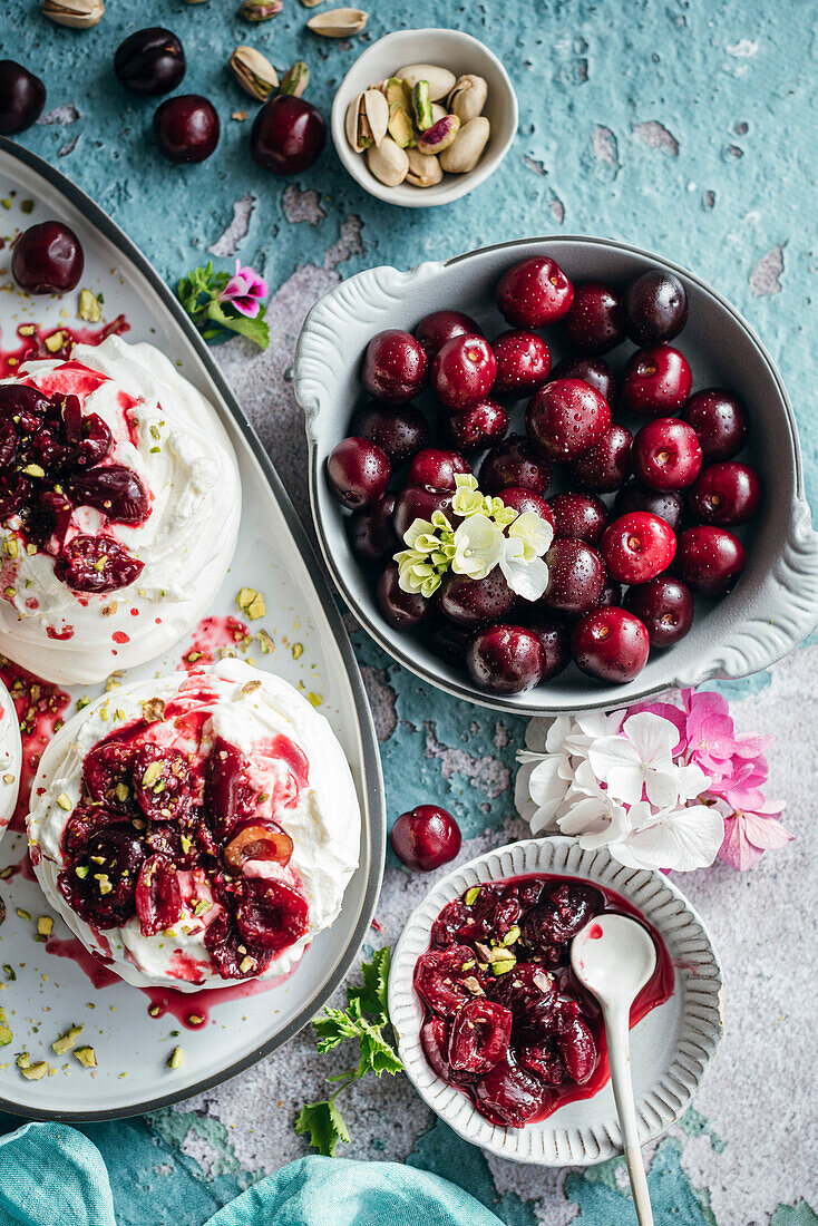 Meringues mit frischer Sahne und reifen Kirschen auf blauem Hintergrund