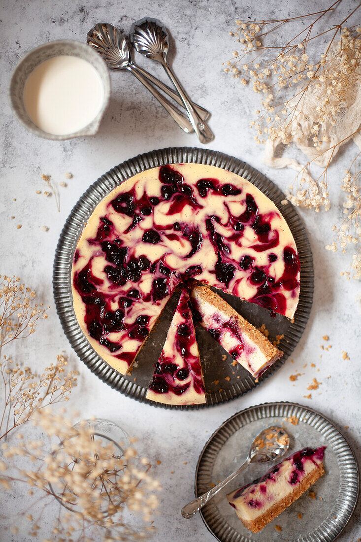 Ein Käsekuchen mit Johannisbeerkompott, von dem mehrere Scheiben abgeschnitten worden sind