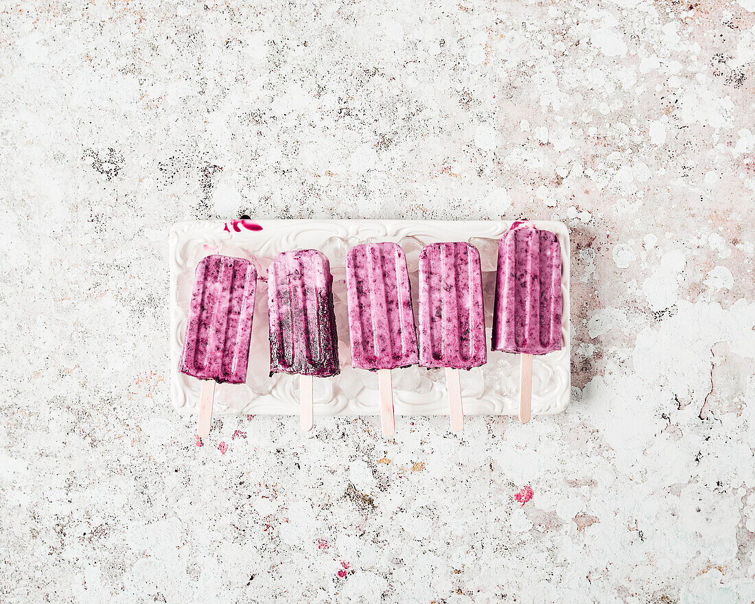 Vegan cherry and coconut ice cream on a stick on a white plate