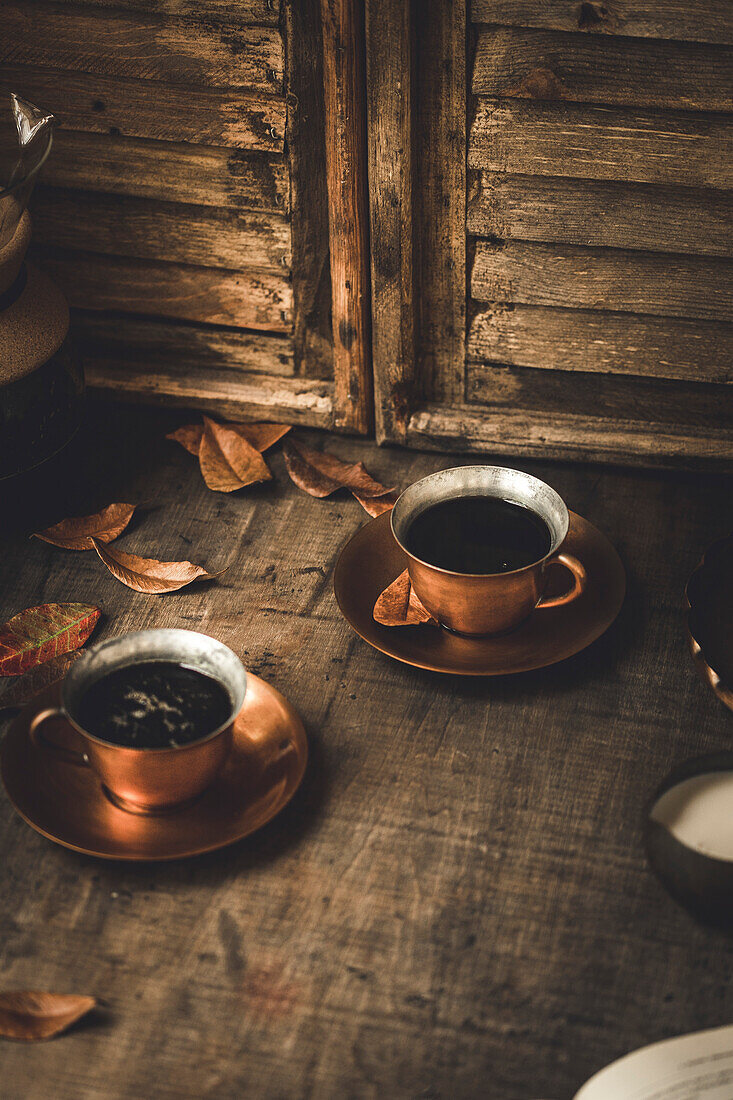 Frischer schwarzer Kaffee, serviert in einer Kupfertasse mit Untertasse