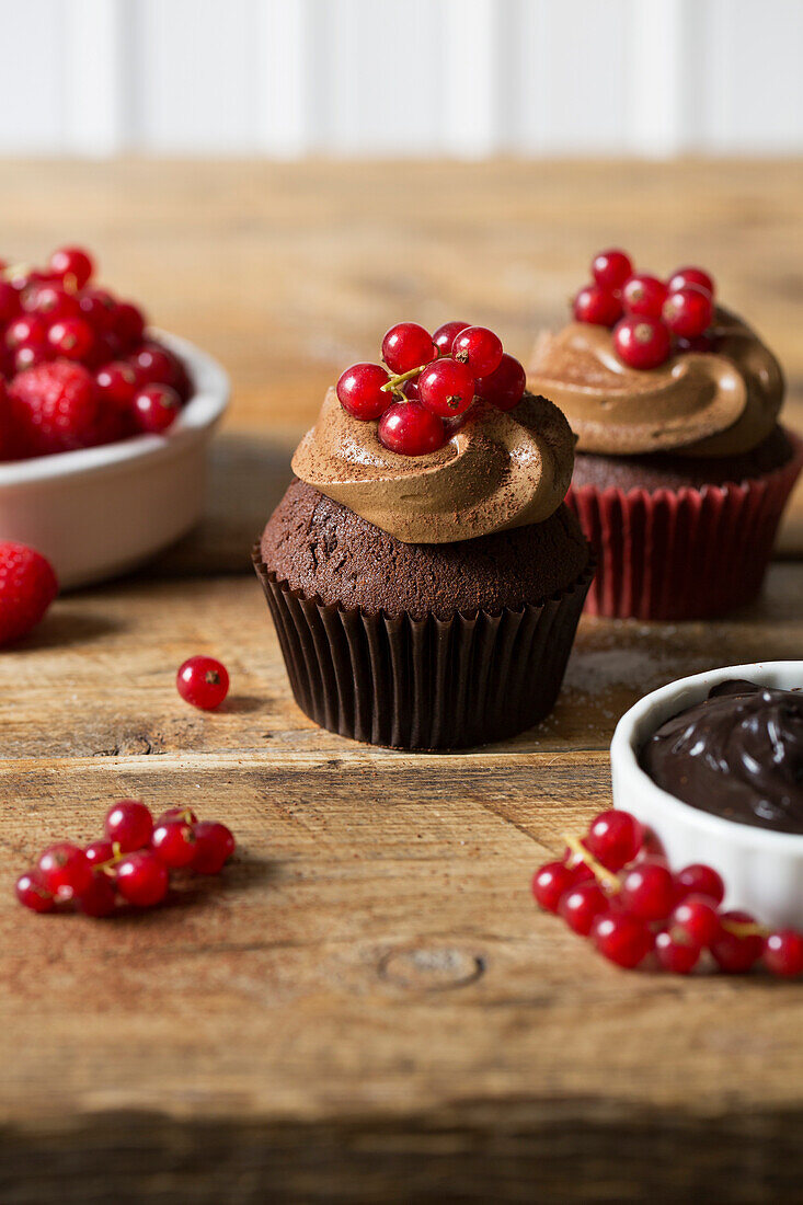 Schokoladen-Cupcake mit roten Früchten auf Holztisch