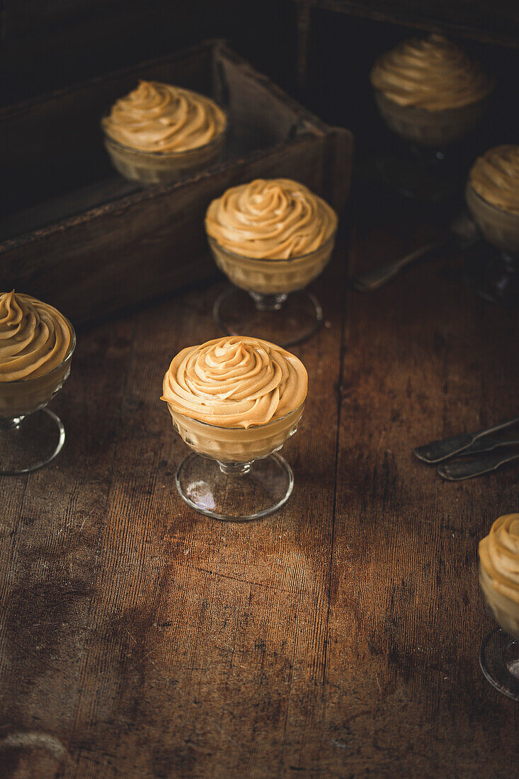 Puddingtassen mit Orangenmousse auf einem Holzuntergrund