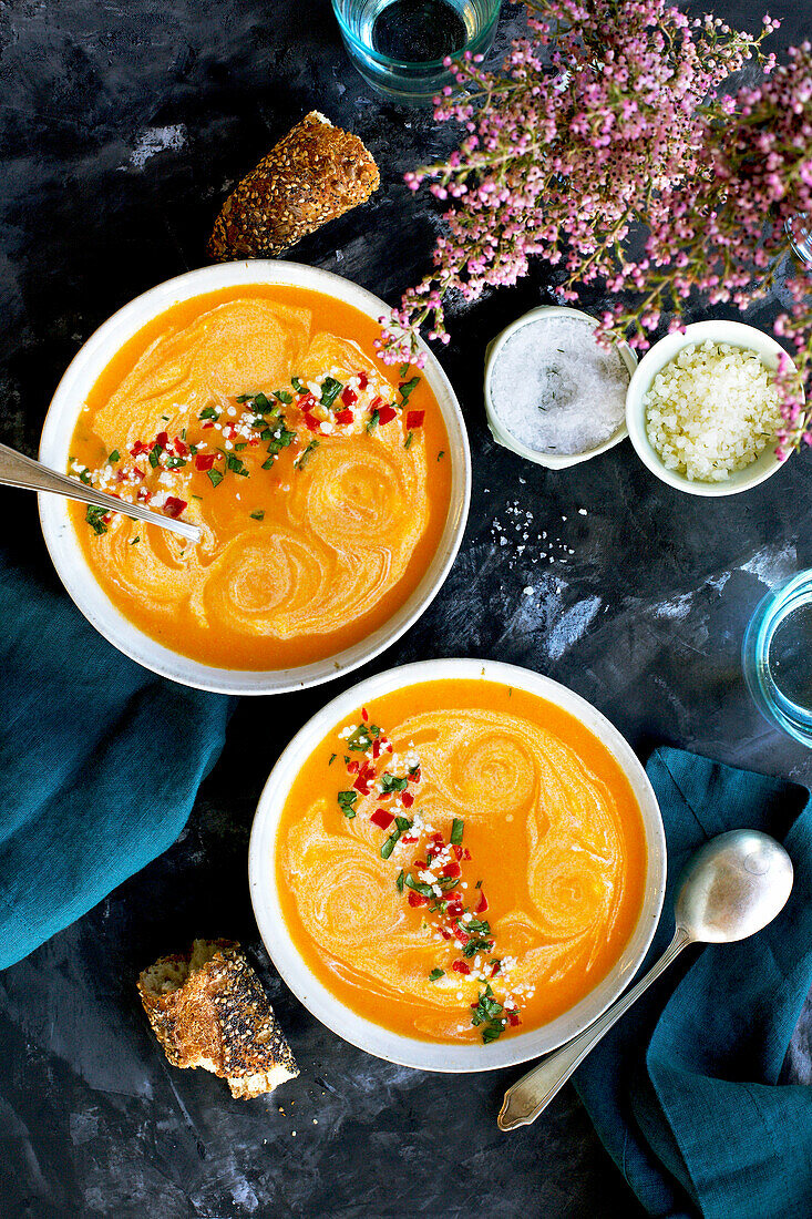 Red lentil-piquillo-paprika bisque in white bowls with blue napkins