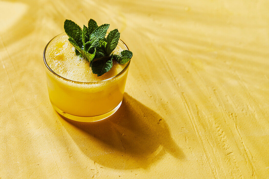 Pineapple and mint G&T on a yellow background with shadows