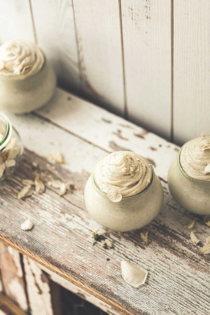 Vanilla mousse dessert served in a glass on a rustic wooden shelf