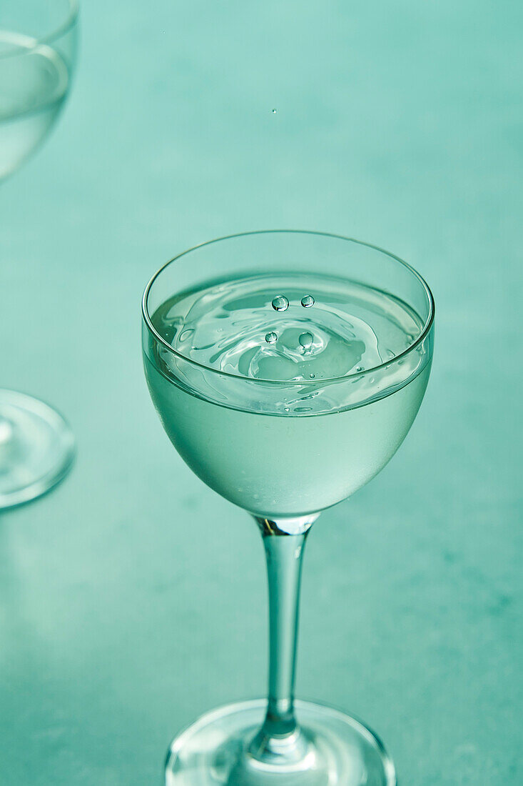 Trockener Martini mit Limette auf salbeigrünem Hintergrund