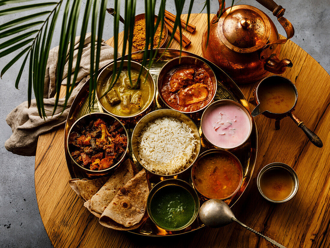 Indisches Essen Thali Gericht nach indischer Art mit Hühnerfleisch und Masala Tee Chai auf Holztisch