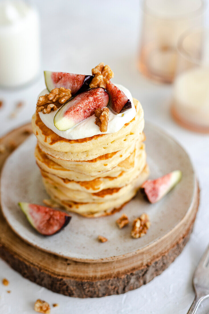 Pancake stack with cream, figs, walnuts and honey on a rustic base