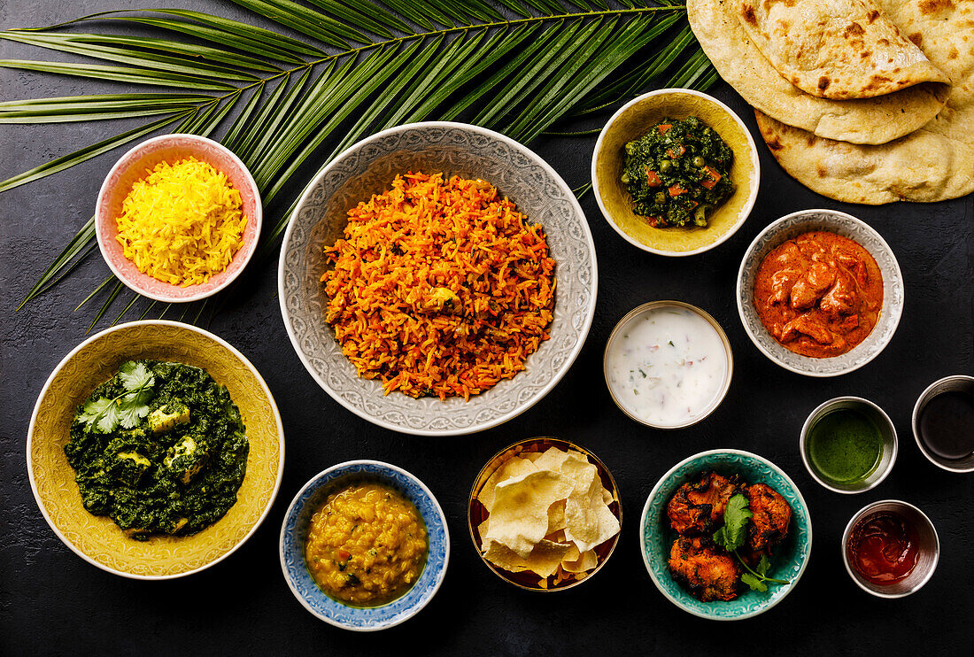 Indisches Essen Curry-Butterhuhn, Palak Paneer, Chiken Tikka, Biryani, Papad, Dal, Reis mit Safran und Naan-Brot auf weißem Hintergrund