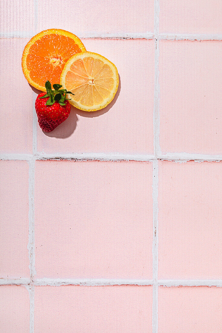 Orangenscheibe, Zitronenscheibe und Erdbeere auf rosa Hintergrund, Sommerfeeling, Kopierraum