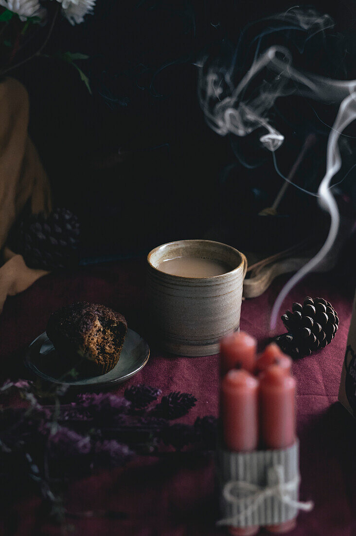 Englischer Nachmittagstee mit Muffin und Kerzen in einem stimmungsvollen und dunklen Stil