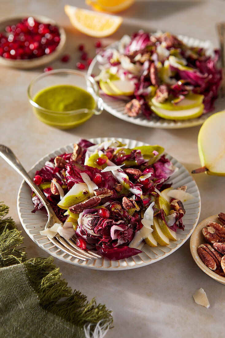 Radicchio salad with pears, pecans, pomegranate, pecans and basil vinaigrette on a neutral brown background with a green cloth