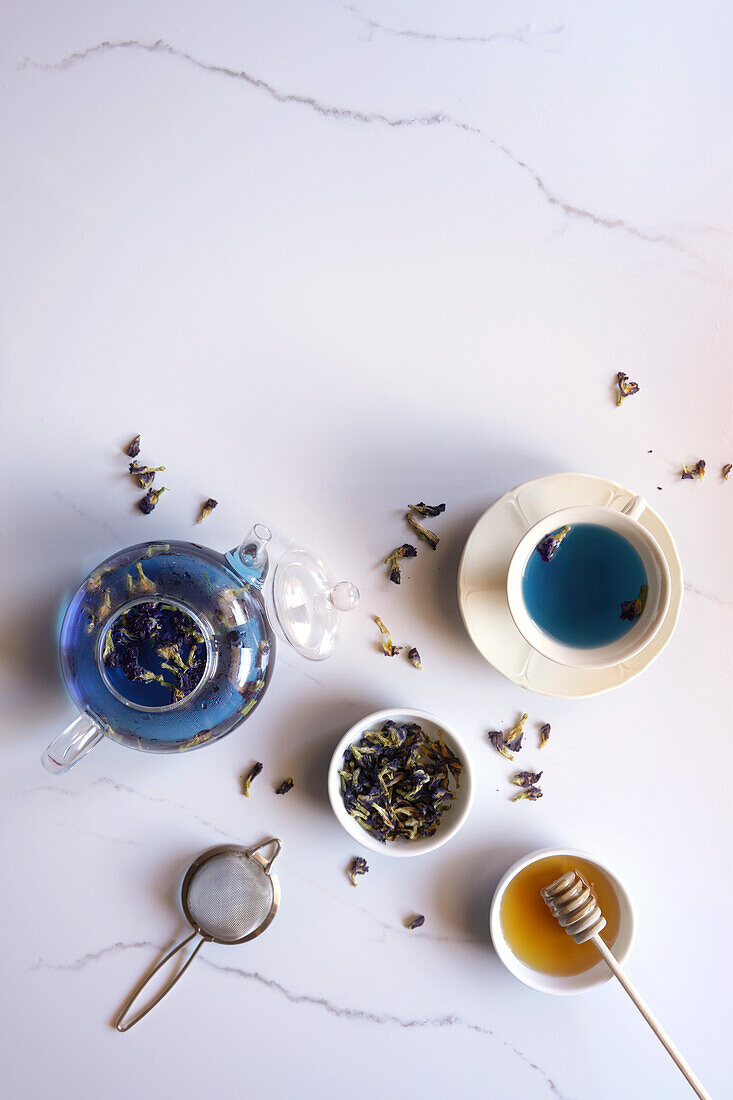 Blue butterfly flower tea on white marble background, top view, flatlay, with negative copy space